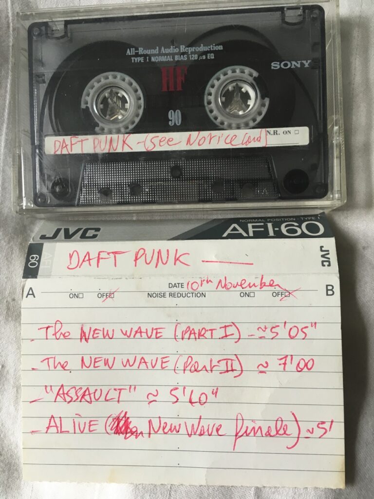 Photo d'une cassette audio Sony 90 et de sa fiche JVC manuscrite listant les morceaux "The New Wave", "Assault" et "Alive" datée du 10 novembre.