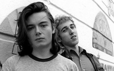 Portrait en noir et blanc de Thomas Bangalter et Guy-Manuel de Homem-Christo jeunes, posant sans masque contre un mur orné de logos de labels de musique.