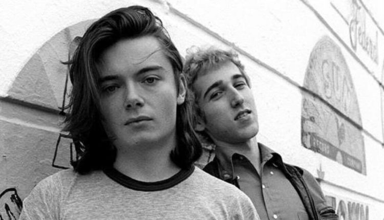 Portrait en noir et blanc de Thomas Bangalter et Guy-Manuel de Homem-Christo jeunes, posant sans masque contre un mur orné de logos de labels de musique.